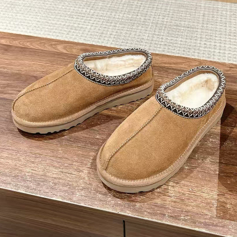 Pair of brown slippers with fur trim on a wooden surface