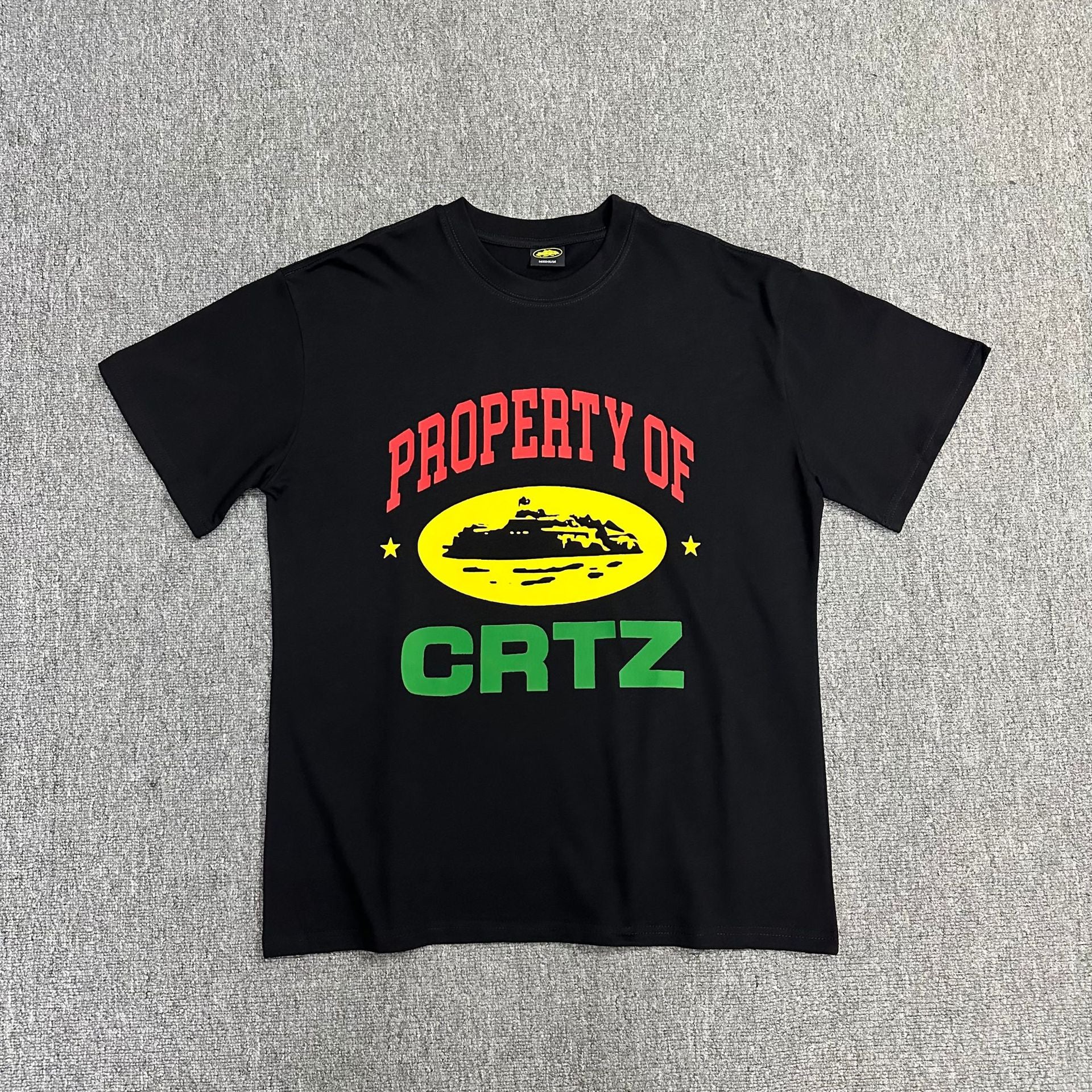 Black t-shirt with colorful graphics and text on a gray textured background