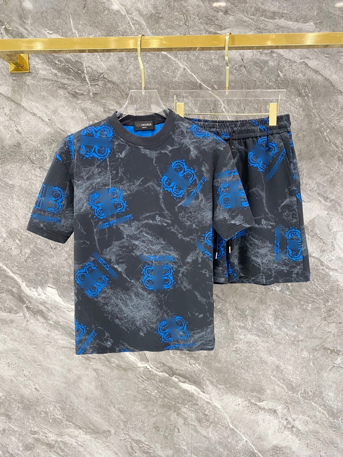 Gray t-shirt and shorts set with blue logo pattern on a marble surface