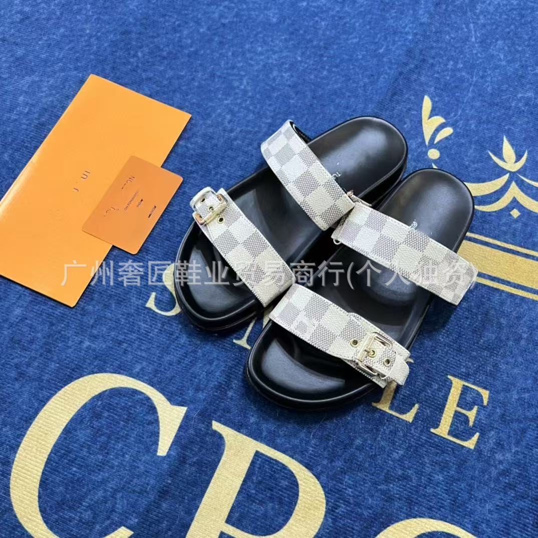 Black slides with patterned straps on a blue surface