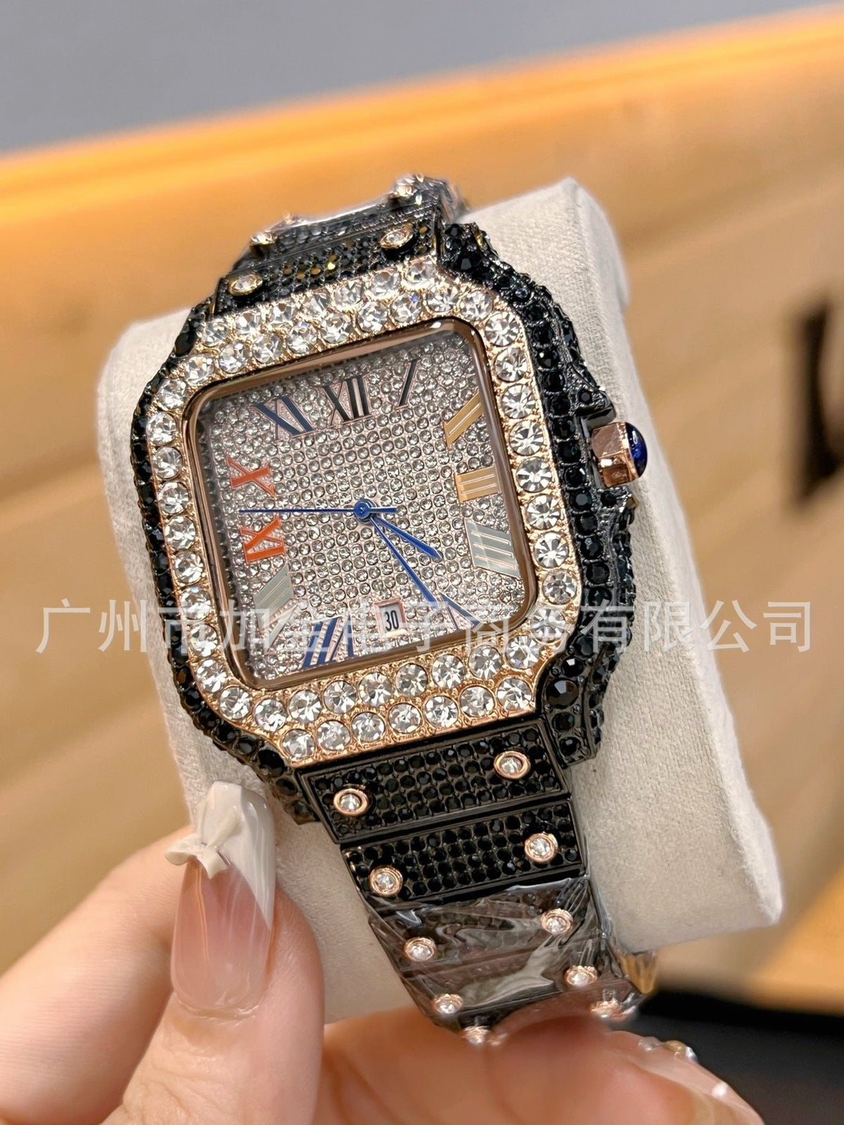 A luxury watch with a textured black crocodile skin strap, a diamond-encrusted silver-toned bezel, and a silver dial with Roman numerals, held by a hand on a white display cushion.