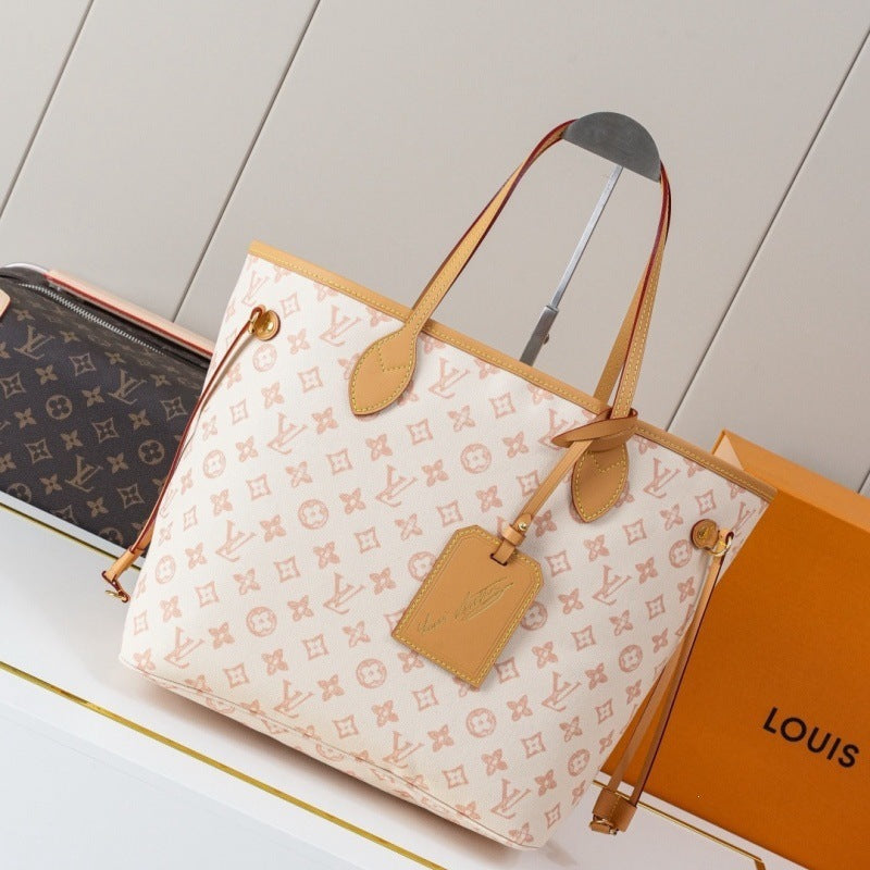 Designer handbag with monogram pattern and matching pouch on a light wooden surface.