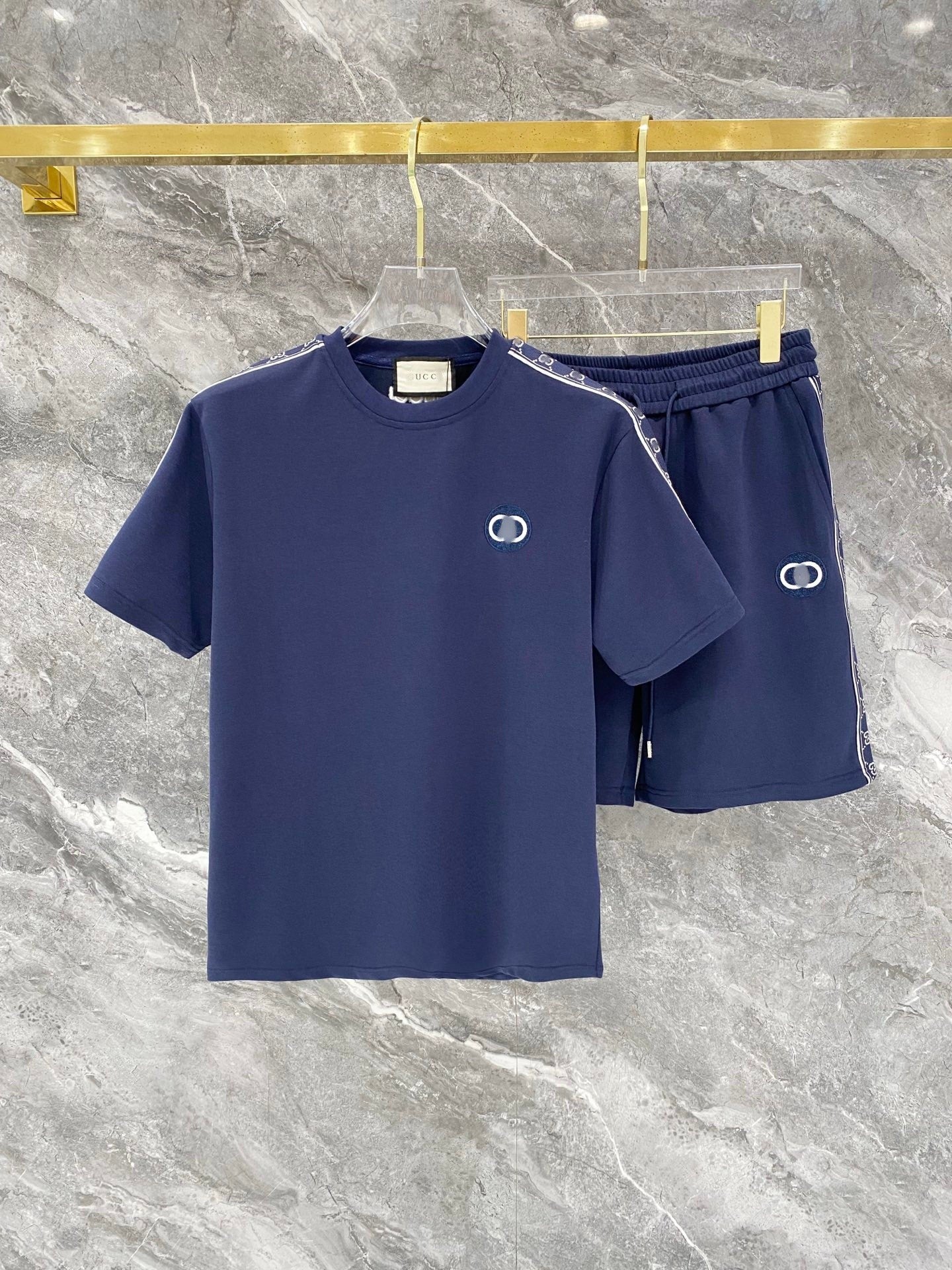 Navy blue t-shirt and shorts set with brand logo on a marble surface