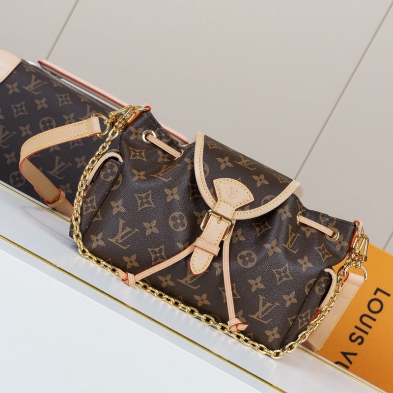 Louis Vuitton monogram shoulder bag in brown coated canvas with beige leather trim and a gold-tone chain strap, shown on a white surface with part of an orange Louis Vuitton box visible.