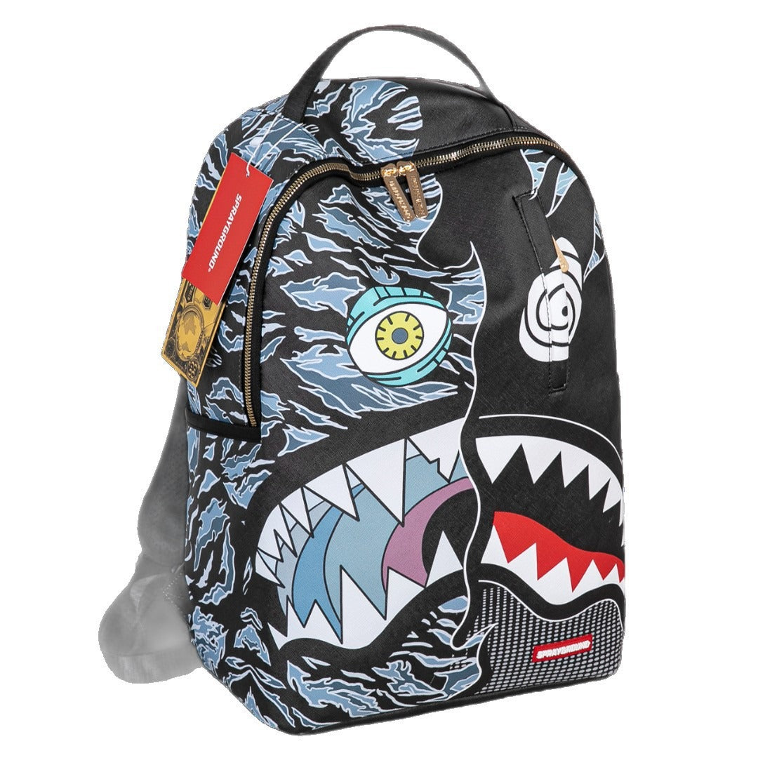 A Spraycraft backpack featuring a shark face graphic in black, blue, white, red, and yellow, with a red Spraycraft brand tag hanging from the side zipper.