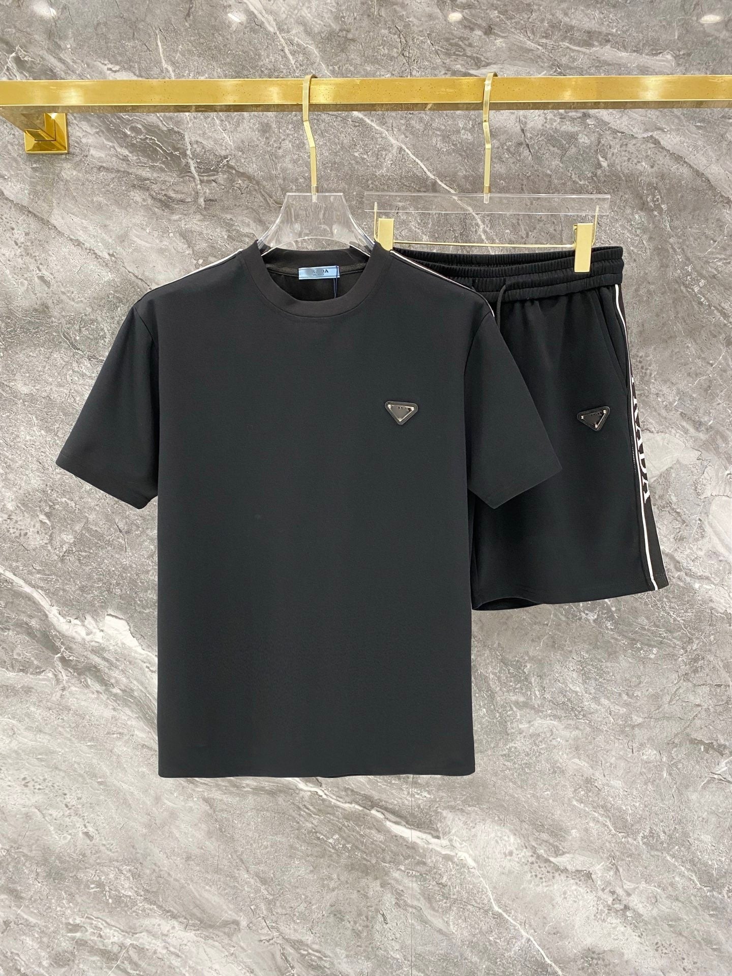 Black t-shirt and shorts set with brand logo on a marble surface