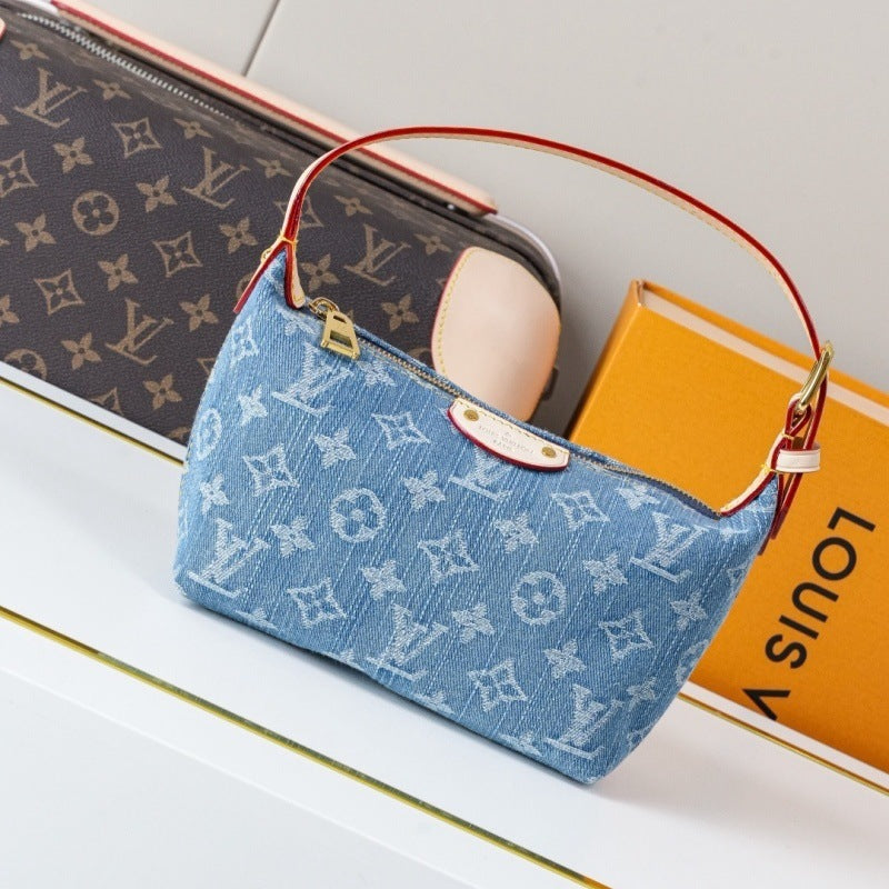 A Louis Vuitton monogram canvas shoulder bag in light blue, styled on a white surface next to a Louis Vuitton monogram pouch and an orange Louis Vuitton box.