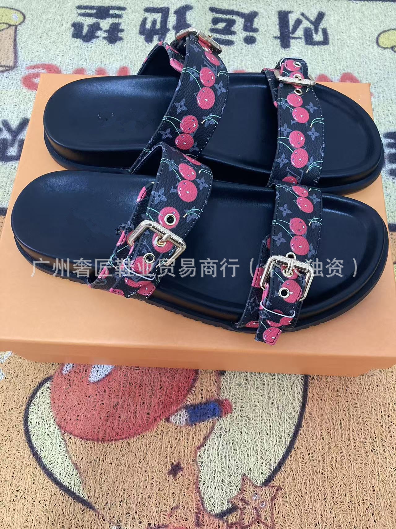 Black sandals with floral straps on a pink box