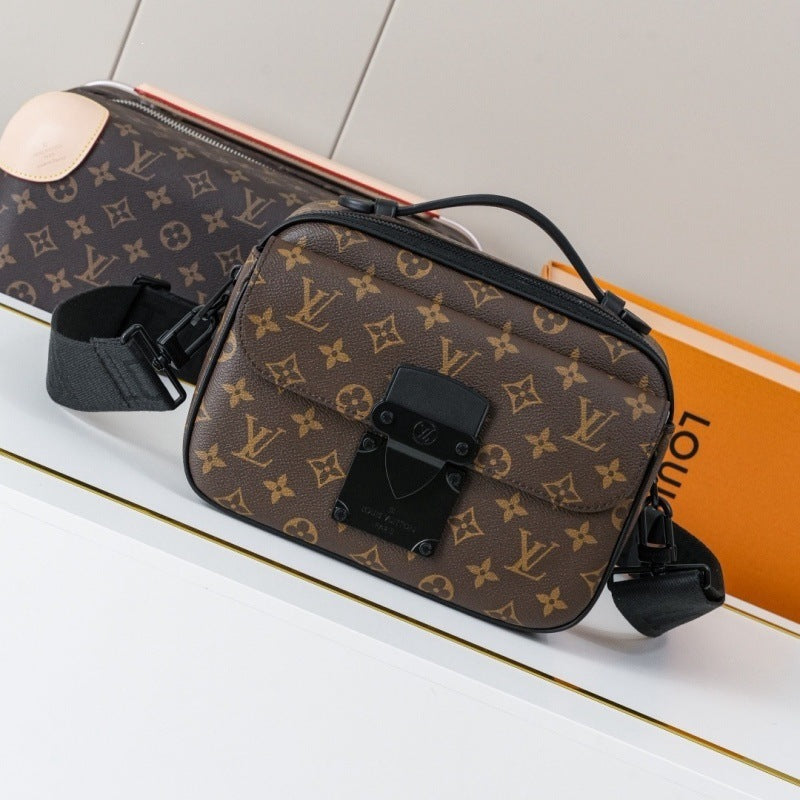 A Louis Vuitton monogram shoulder bag in brown coated canvas with black trim and a black strap, displayed on a white surface with an orange Louis Vuitton box in the background.