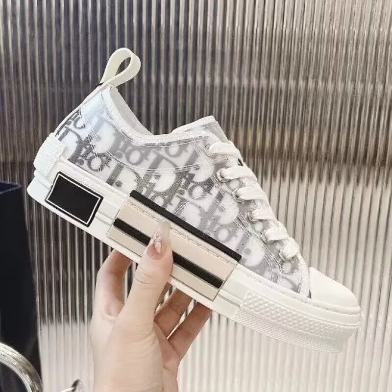 White sneaker with black accents held by a hand against a metallic background