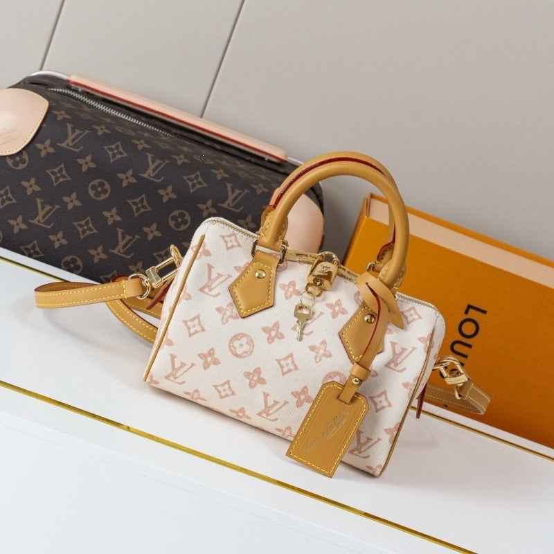 A Louis Vuitton handbag in the brand's signature monogram canvas, featuring a cream and brown pattern with tan leather handles and trim, displayed alongside a matching monogram pouch and orange Louis Vuitton box.