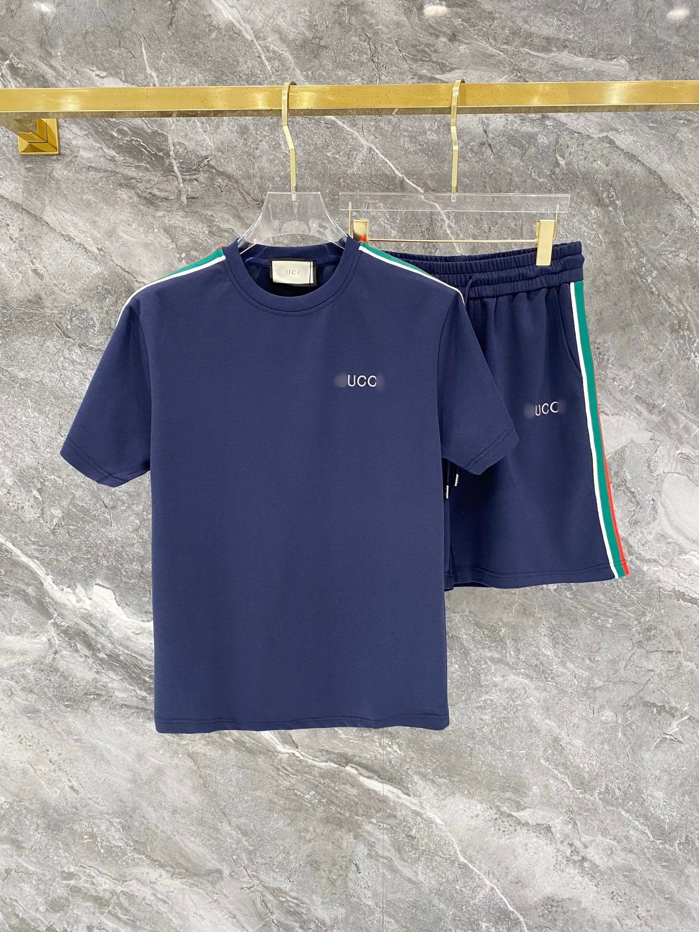 Navy blue t-shirt and shorts set with 'UCC' branding on a marble surface.