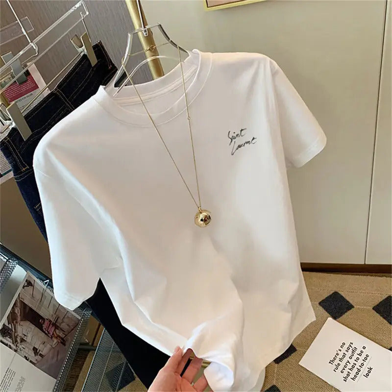 White t-shirt with a small design on a hanger in a room setting.