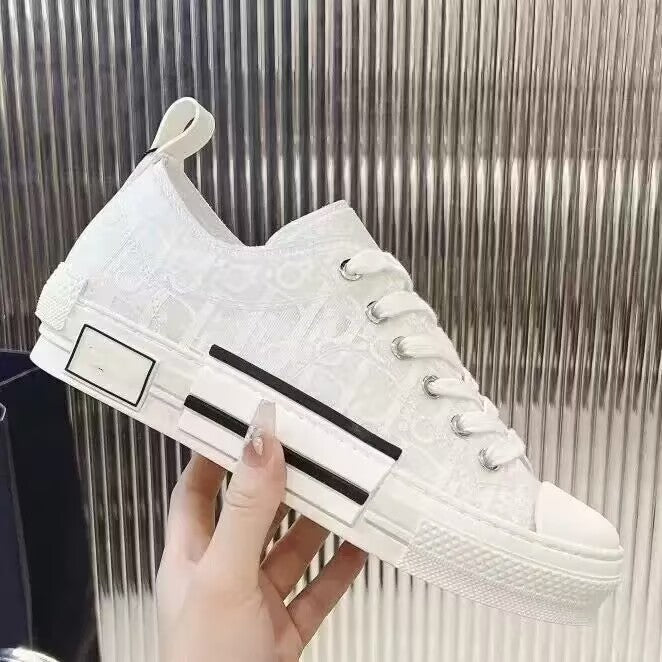 White sneaker with black accents held by a hand against a metallic background