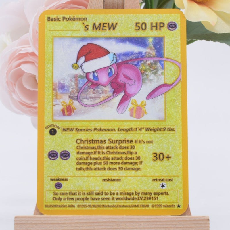 A holographic Pokémon trading card featuring Mew in a Christmas outfit, displayed on a wooden stand with soft pink roses in the background.