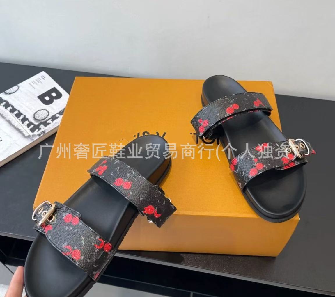 Black sandals with red floral patterns on a black surface
