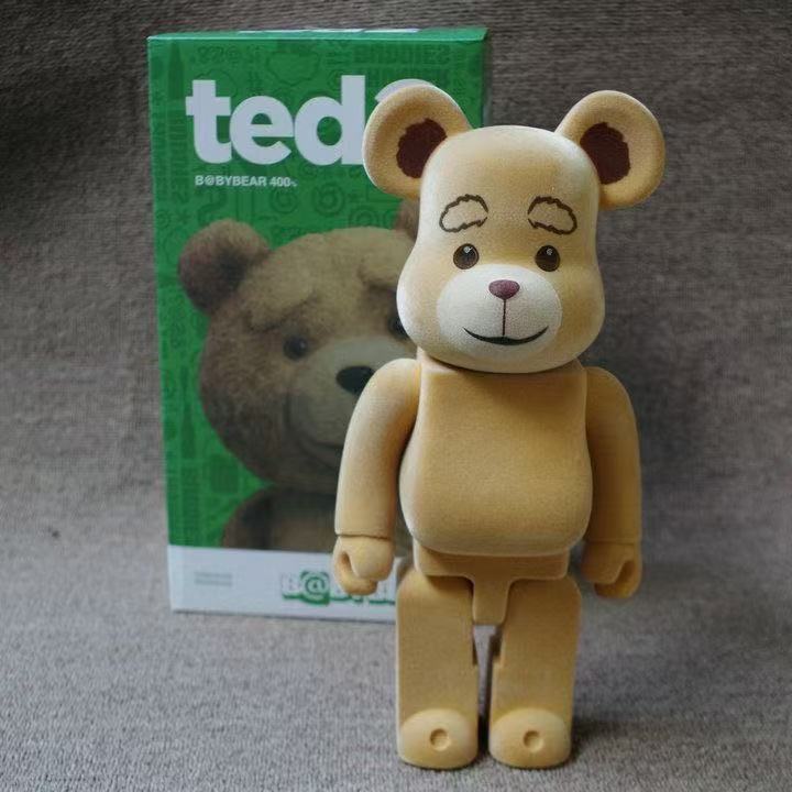 A teddy bear figure standing in front of its green product box, with the brand name 'ted' and 'DEBYEAR 400' visible on the packaging.