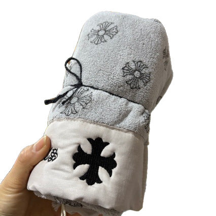 Gray and white towel set with embroidered designs held by a hand on a white background