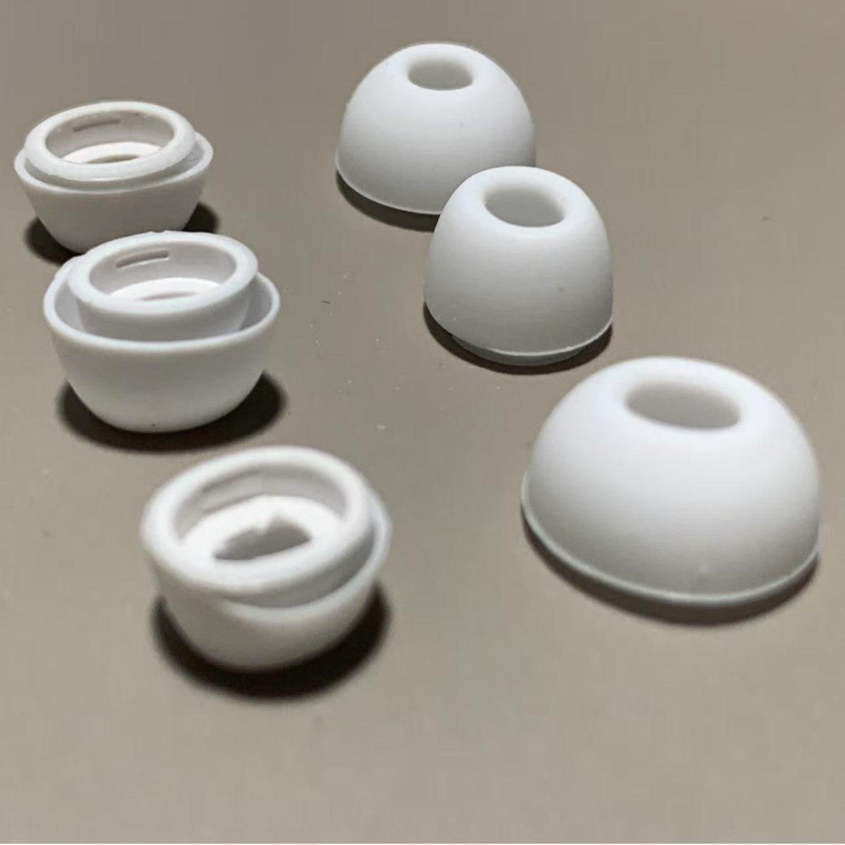 Set of white silicone earbud tips on a beige surface
