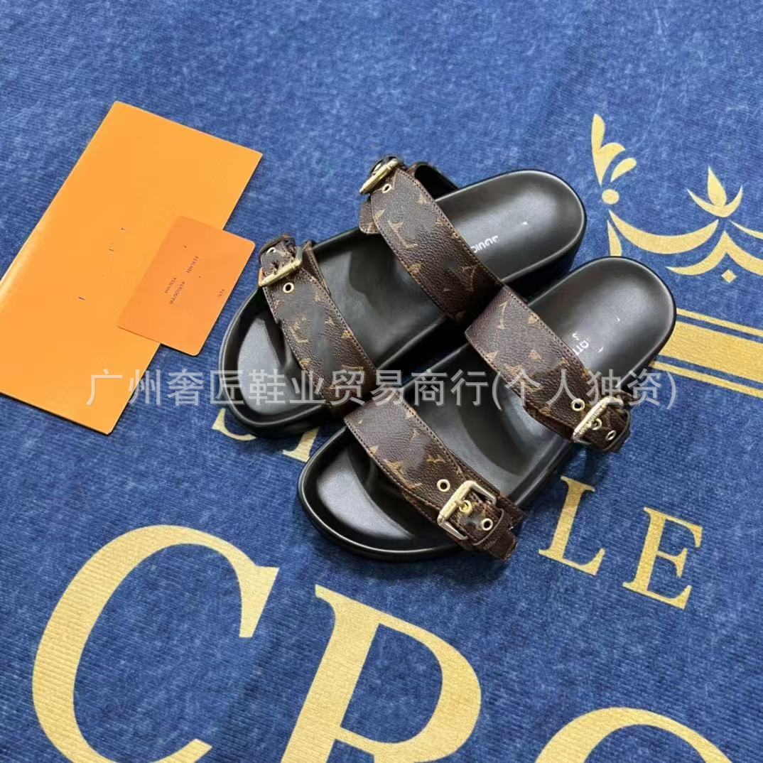 Black sandals with brown straps on a blue surface with gold text