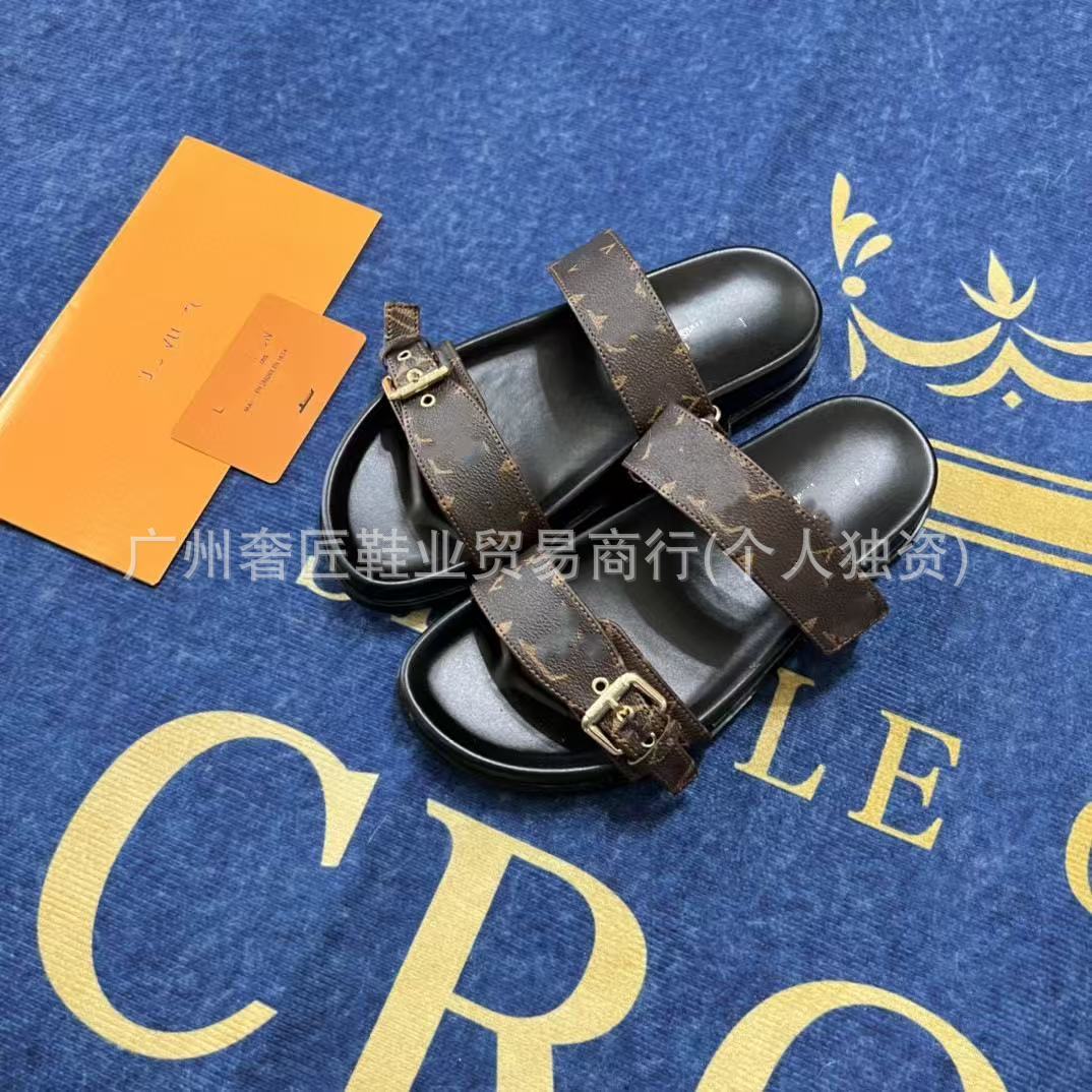 Pair of black sandals with brown straps on a blue surface with gold text