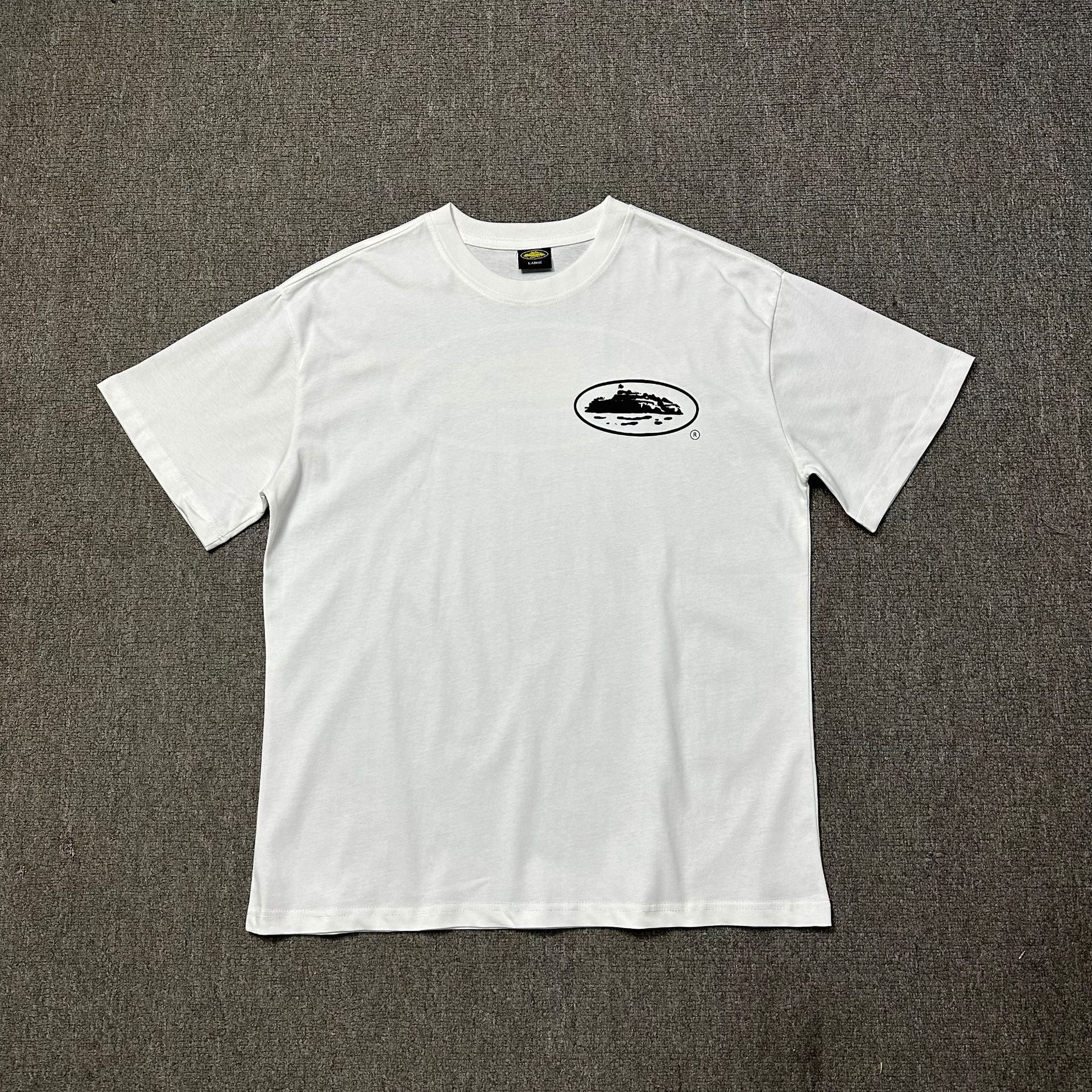 White t-shirt with a small logo on a gray background
