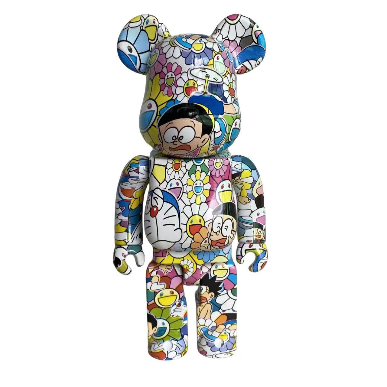 A collectible bear-shaped figure covered in a dense multicolor graffiti-style pattern featuring cartoon characters, flowers, and geometric shapes, shown against a plain white background.