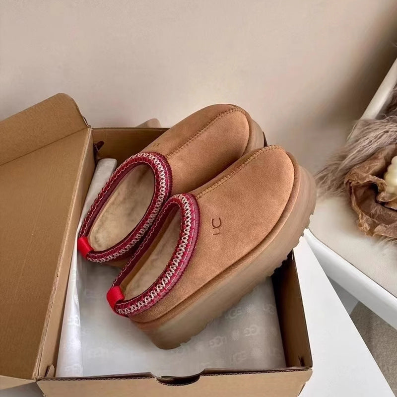 Pair of brown shoes with red soles in a cardboard box on a white surface.