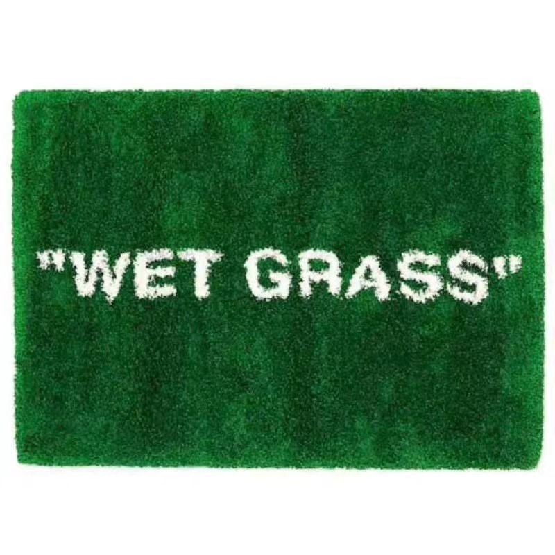 A rectangular green shag rug with the words "WET GRASS" in white fuzzy letters, shown on a plain white background.