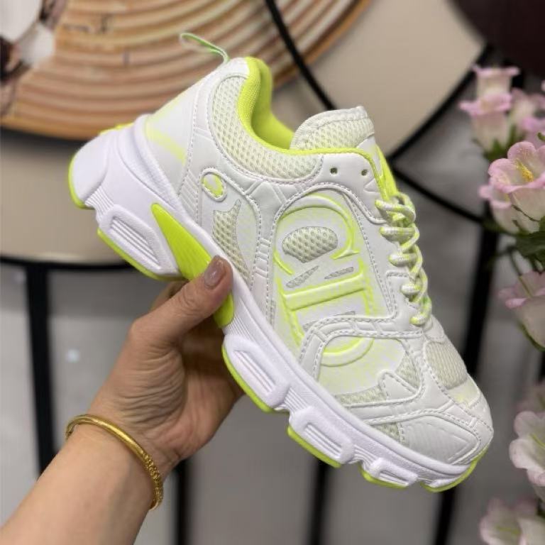 White and neon green sneaker held in a hand with a blurred background