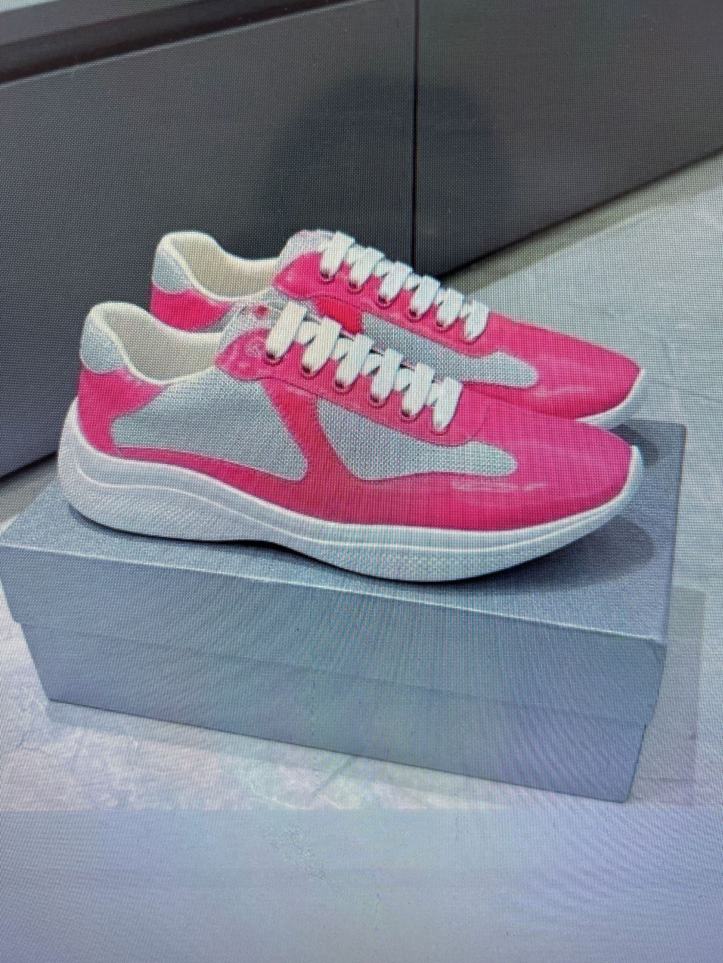 Pink and gray sneakers on a gray platform with a neutral background