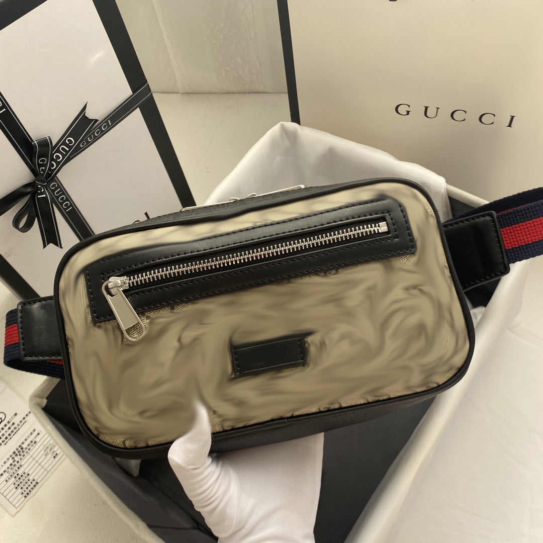 A Gucci shoulder bag with the classic GG Supreme canvas in beige and brown, featuring black leather trim and a black-and-red webbed strap. The bag is held by a white-gloved hand inside a white box, with Gucci packaging boxes visible in the background.