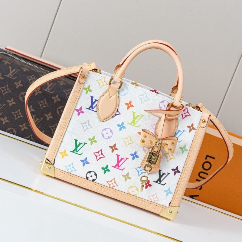 A Louis Vuitton monogram mini top-handle bag in white canvas with a colorful multicolor monogram print, beige leather trim and handles, and gold-tone hardware, displayed on a white surface with a Louis Vuitton box in the background.