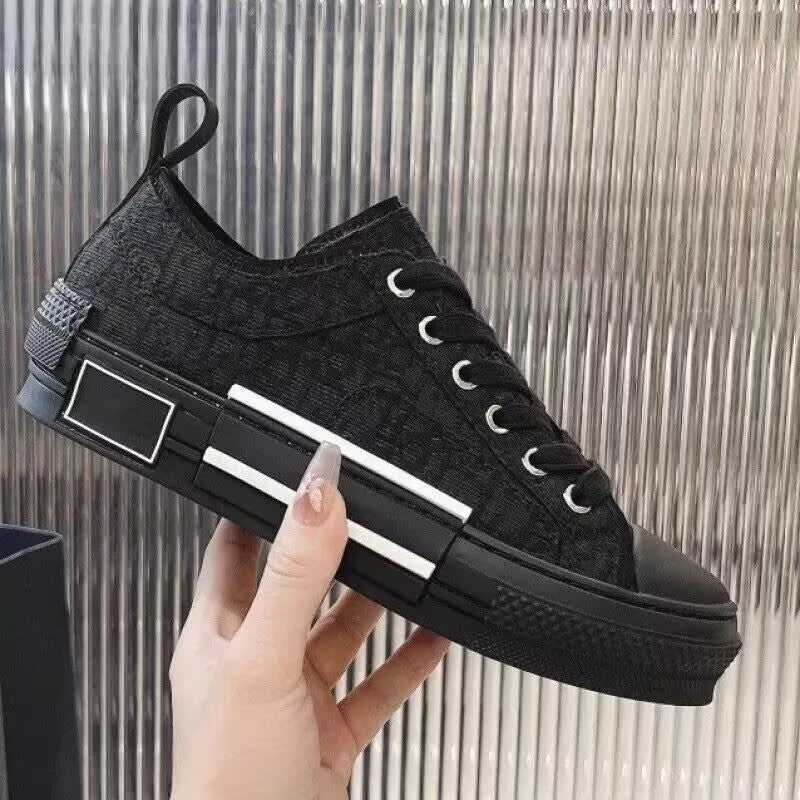 Black sneaker with white stripes held by a hand against a metallic background