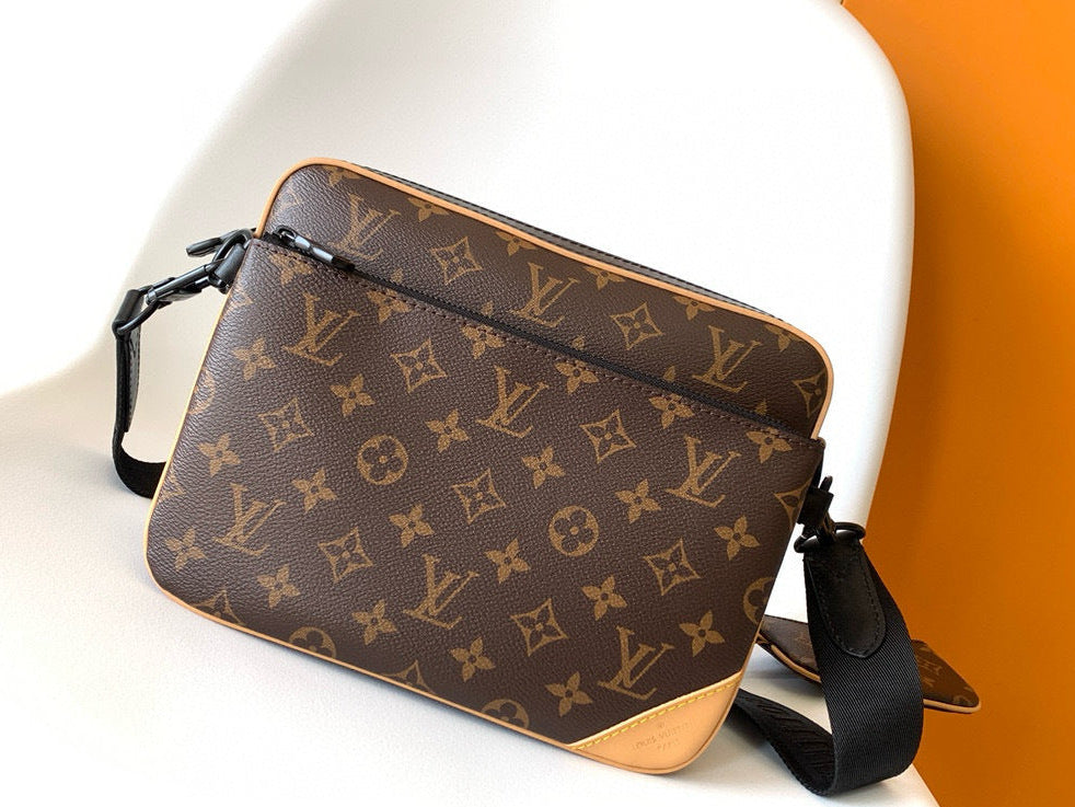 Designer handbag with monogram pattern on a white surface with an orange background
