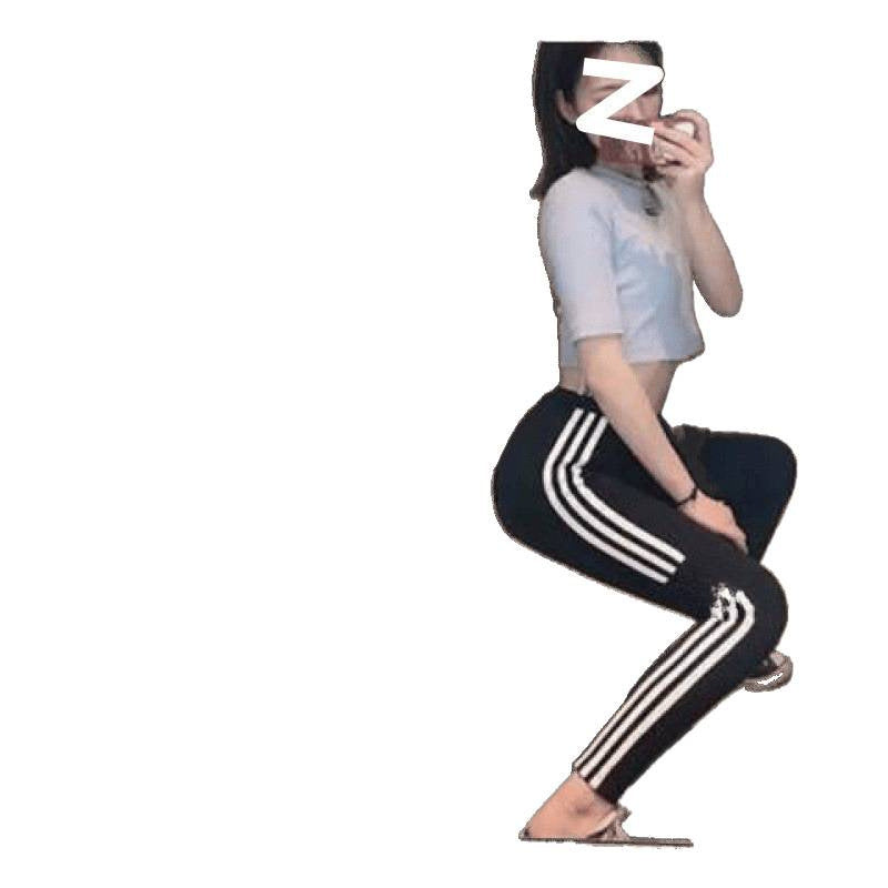 Person wearing black pants with white stripes sitting on a white background