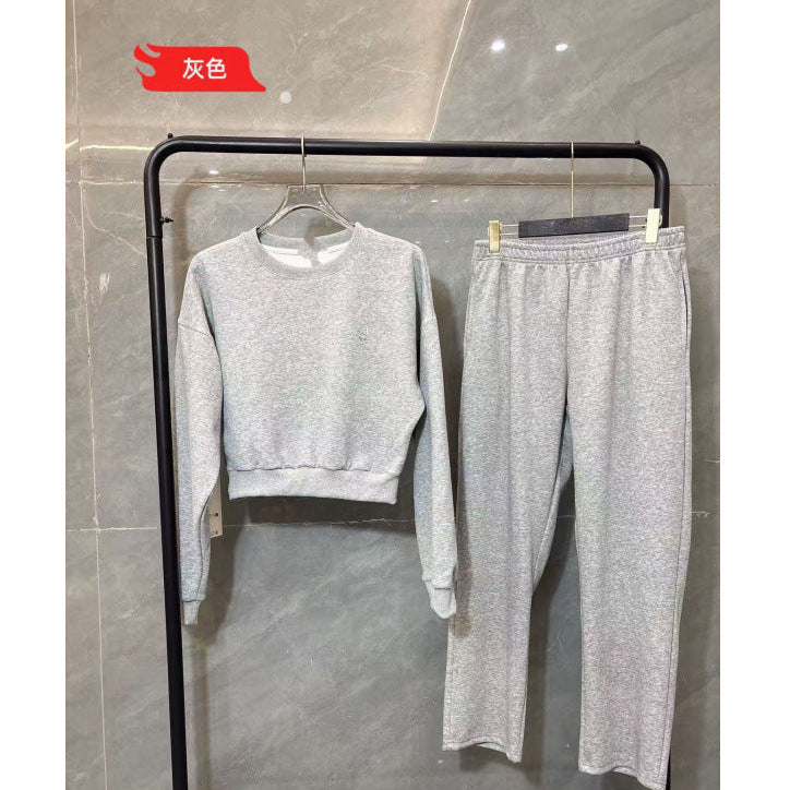 Gray sweater and pants set on a black rack against a tiled wall.