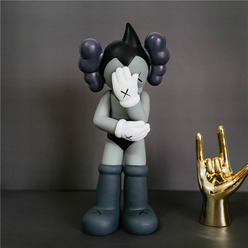 A stylized collectible figurine of a character with dark hair in pigtails, a white face covering, and gray boots, standing against a dark gray background next to a gold hand-shaped object.