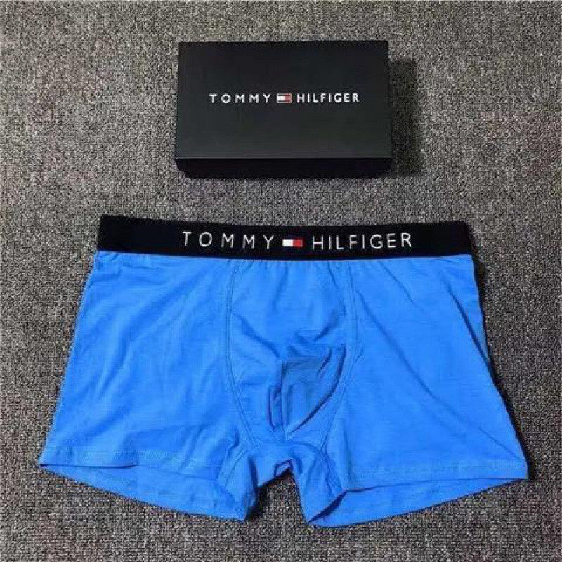 Blue Tommy Hilfiger boxer briefs with black waistband on a textured surface