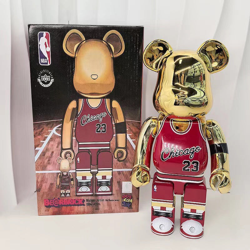 A shiny gold and red Chicago Bears 200 Bearbricks 2 figure stands next to its original black packaging box on a white background.