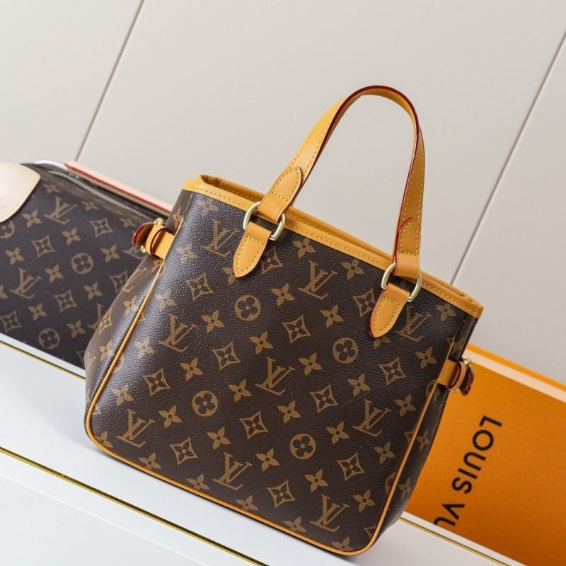 Louis Vuitton monogram canvas handbag in dark brown with tan leather trim and handles, shown on a white surface with part of a matching bag and an orange Louis Vuitton box visible.