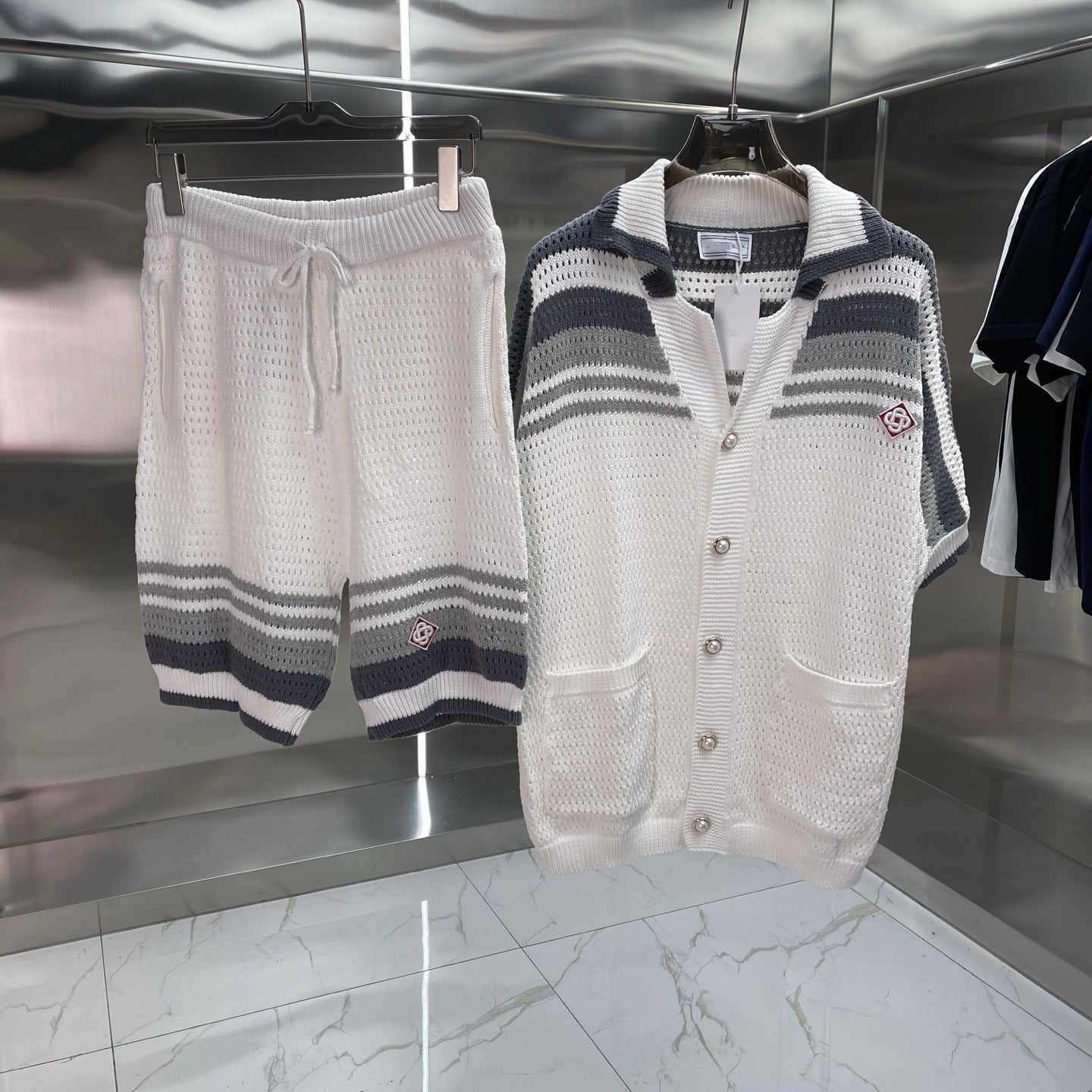 Knitted cardigan and shorts hanging on a rack in a store setting.