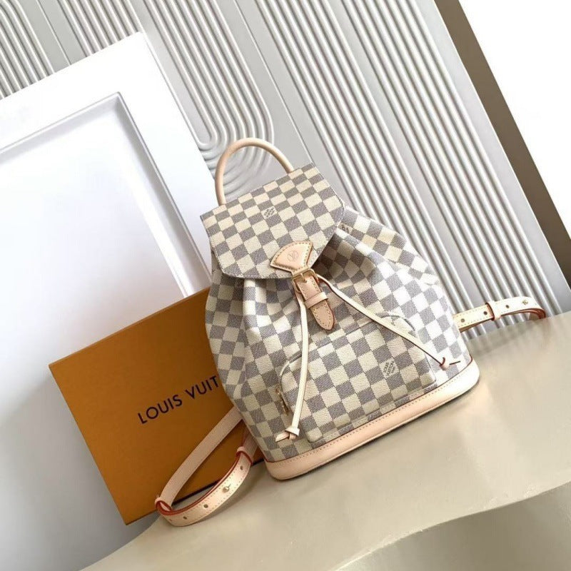 Louis Vuitton Damier Ebene checkered canvas backpack with beige leather trim and drawstring closure, displayed next to its signature brown box on a light beige surface.