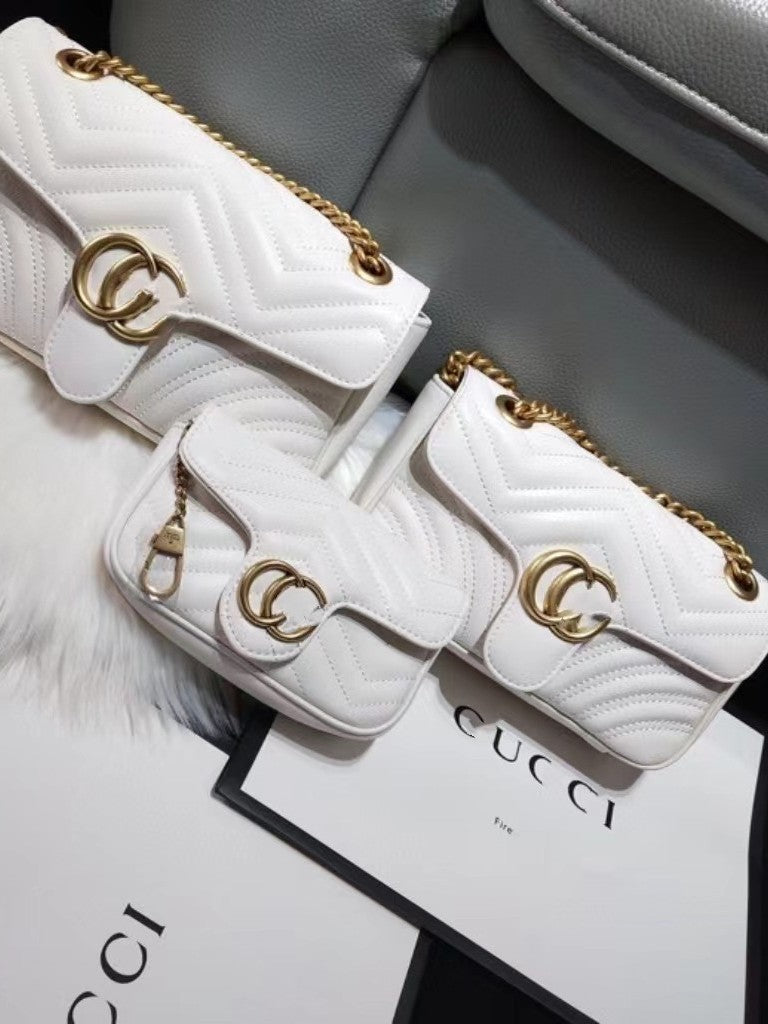 Three white quilted shoulder bags with gold chain straps and interlocking GG hardware displayed on Gucci branded packaging.