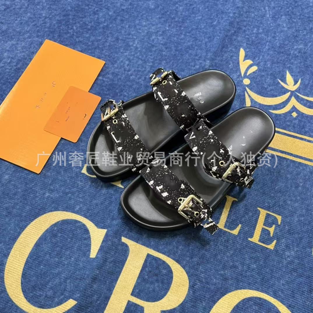 Black sandals with decorative straps on a blue surface with gold text