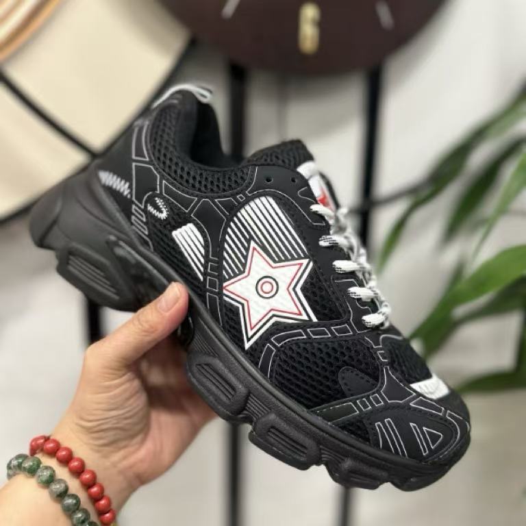 Black sneaker with a red star design held by a hand against a blurred background