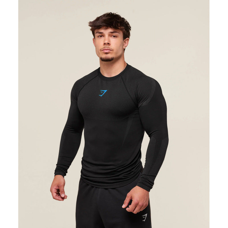 Man wearing a black long-sleeve athletic shirt with a logo on a beige background