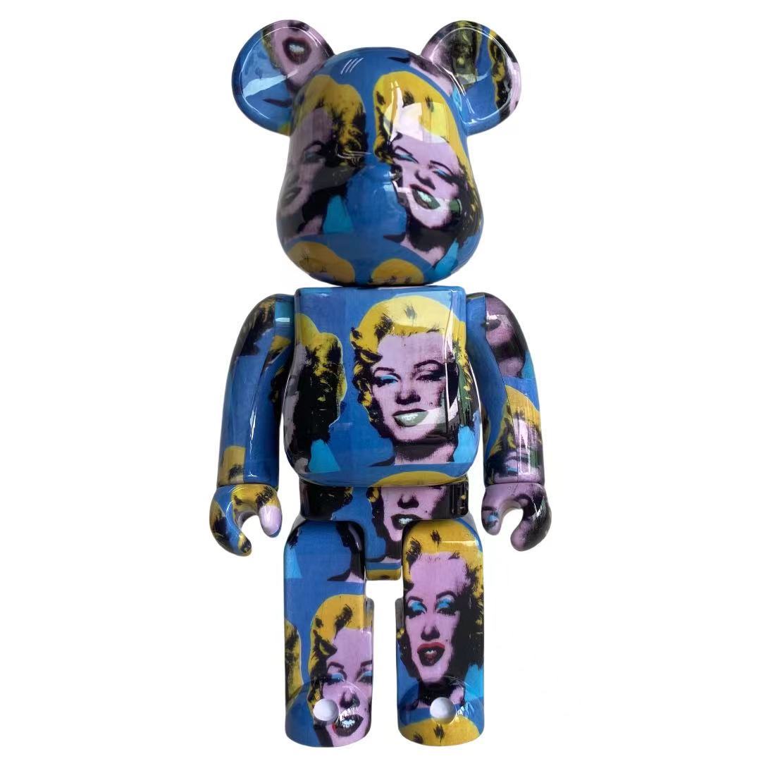 A collectible bear-shaped figure with a glossy blue and purple Marilyn Monroe pop-art print, set against a plain white background.