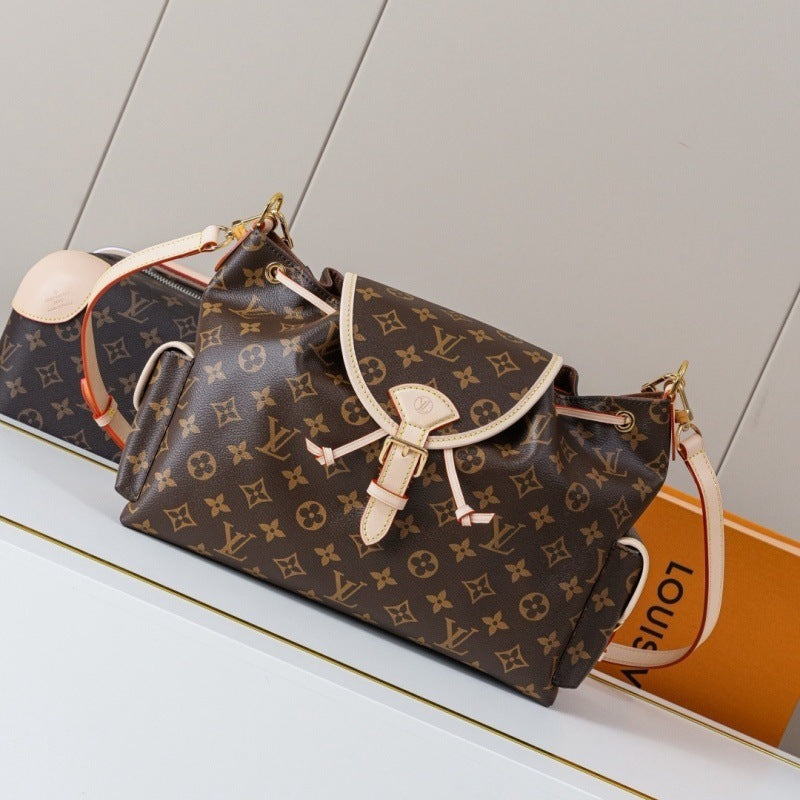 A Louis Vuitton monogram shoulder bag in brown coated canvas with beige leather trim and gold-tone hardware, shown resting on a white surface with part of an orange Louis Vuitton box visible in the background.