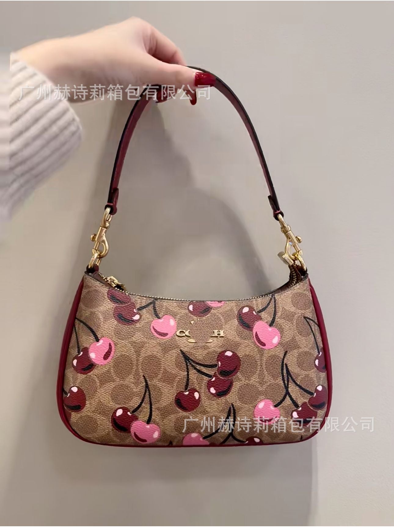 Handbag with cherry design held by a person against a light background